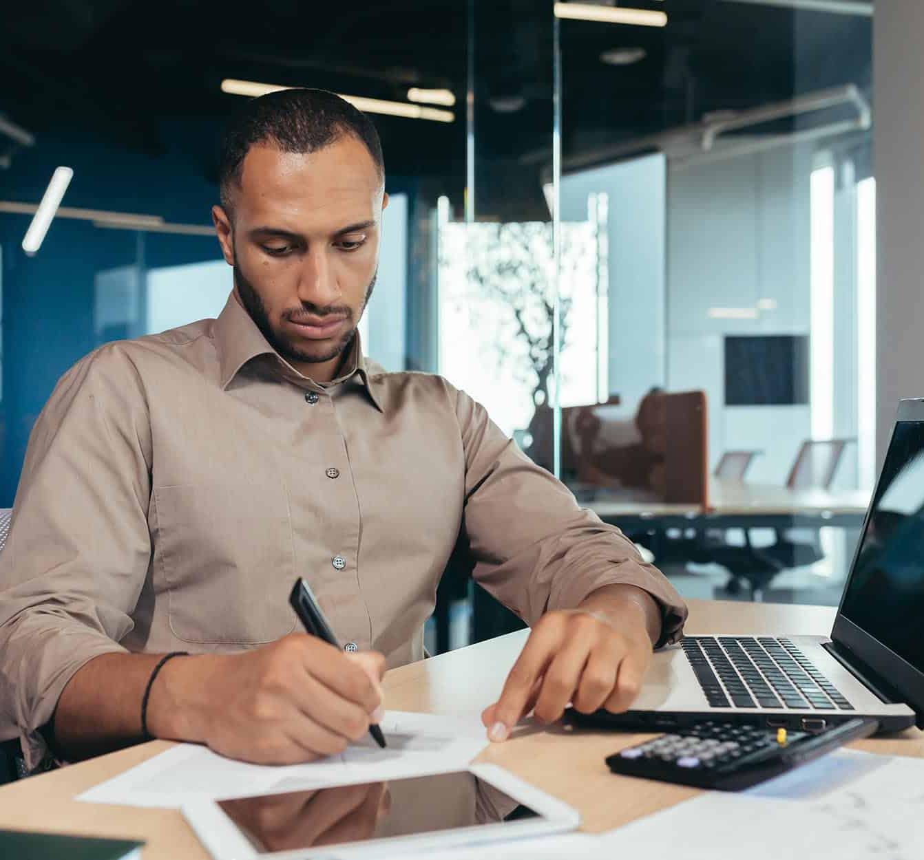 Employee-using-laptop-and-looking-through-papers-narrow