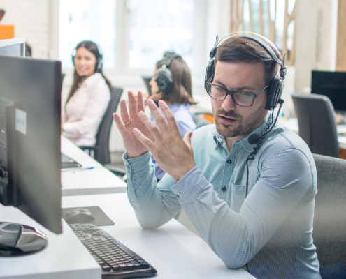 Young handsome male technical support agent trying to explain something to a client